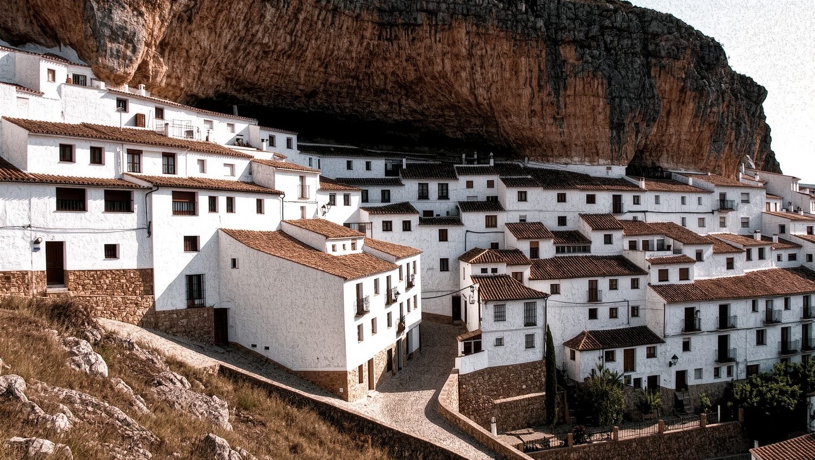 Pueblo blanco andaluz construido bajo una roca, ruta de los Pueblos Blancos, ilustración estilo grunge retro
